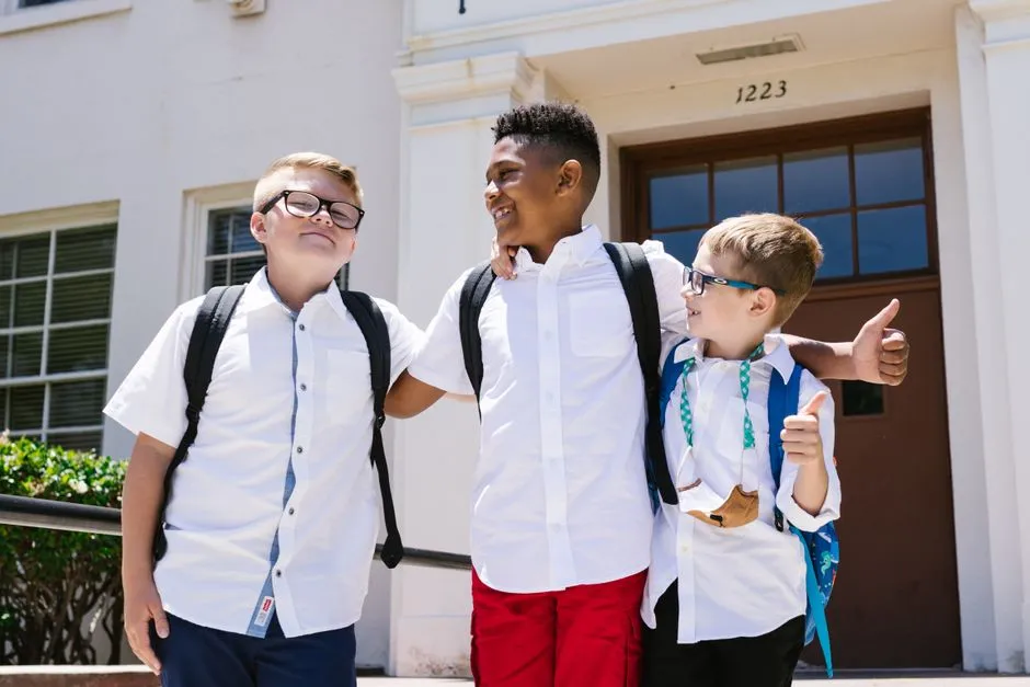 Students smiling near a school entrance on the first day of the school year